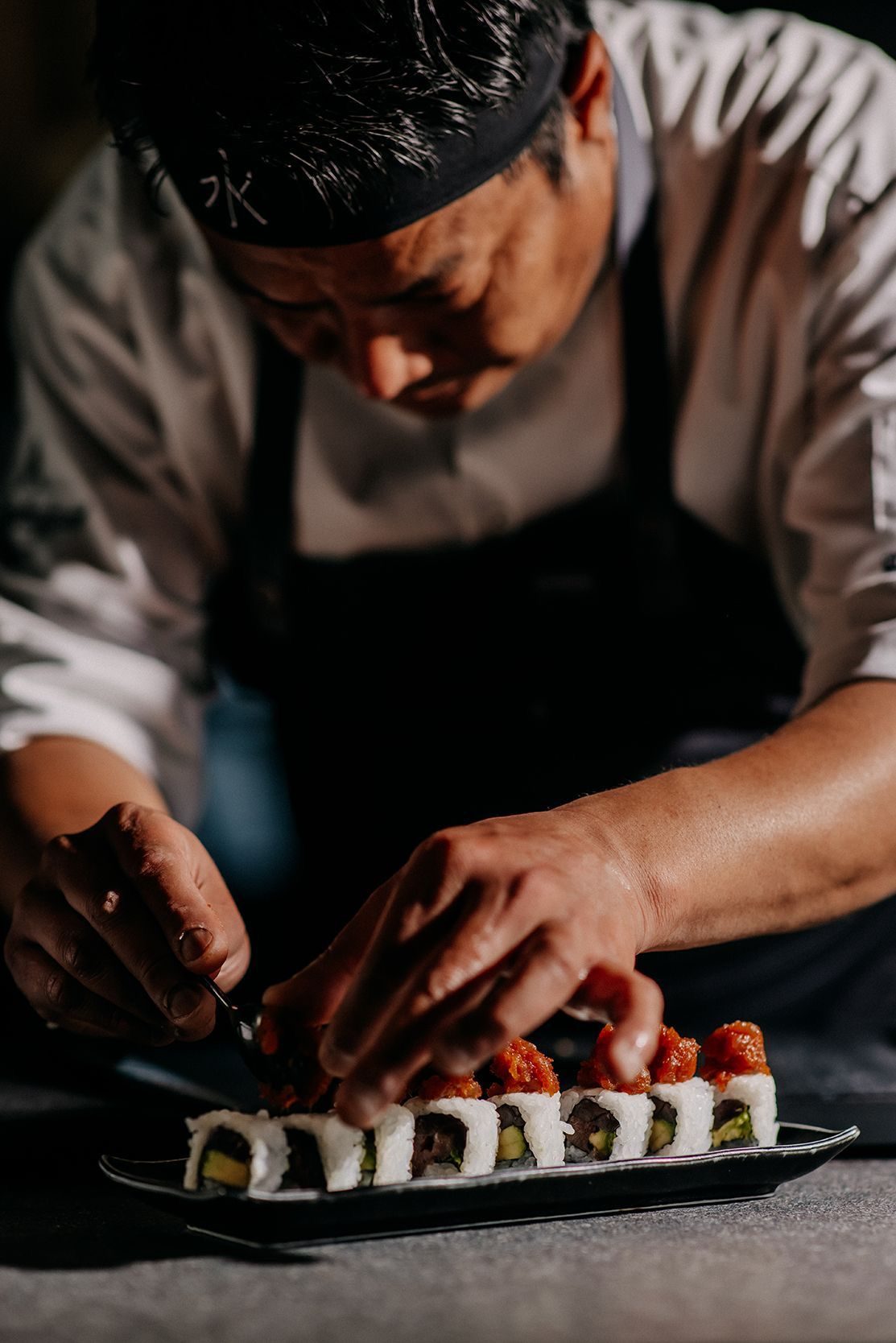 A chef finishing a roll at the sushi counter