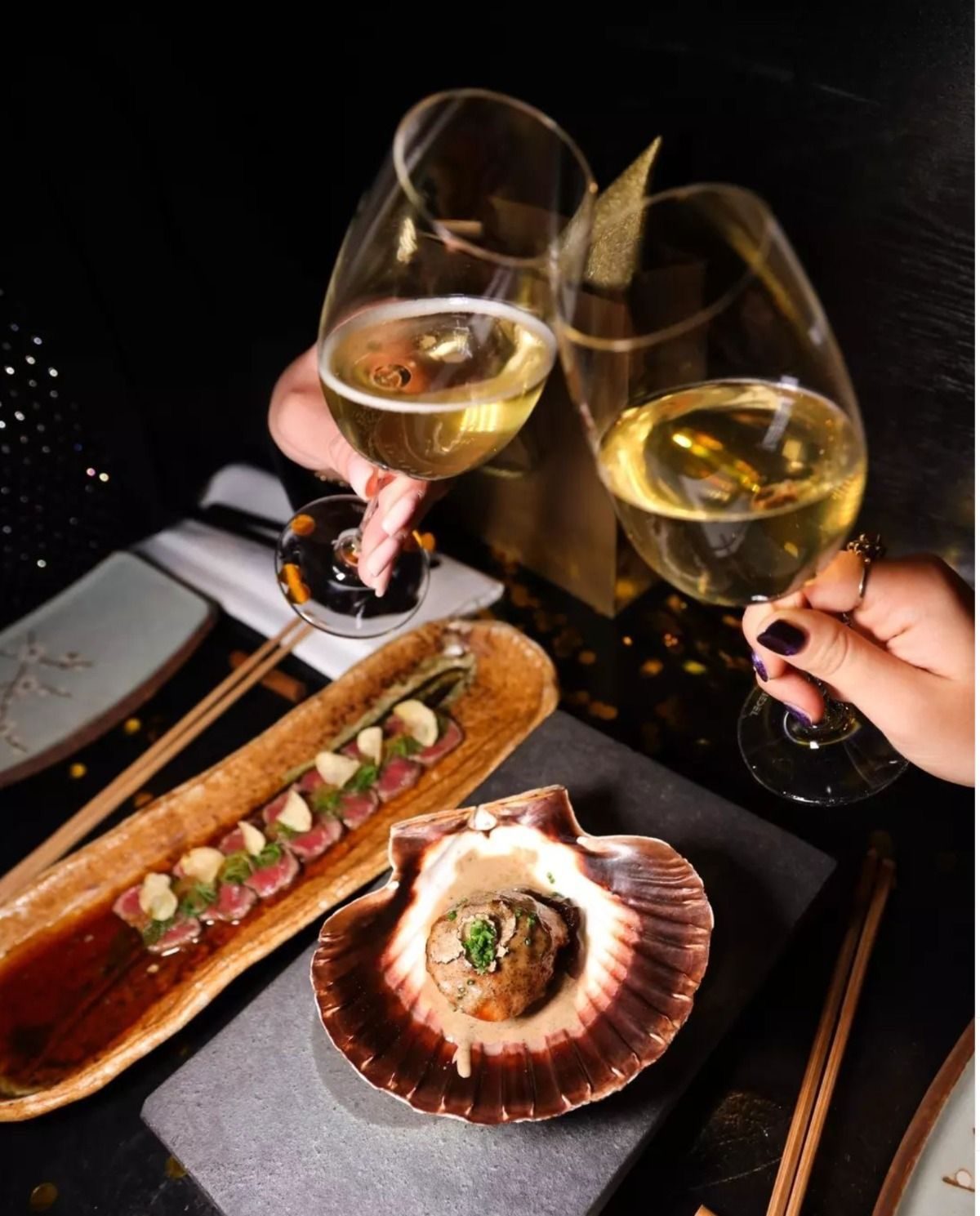Two guests raising wine glasses over a set table