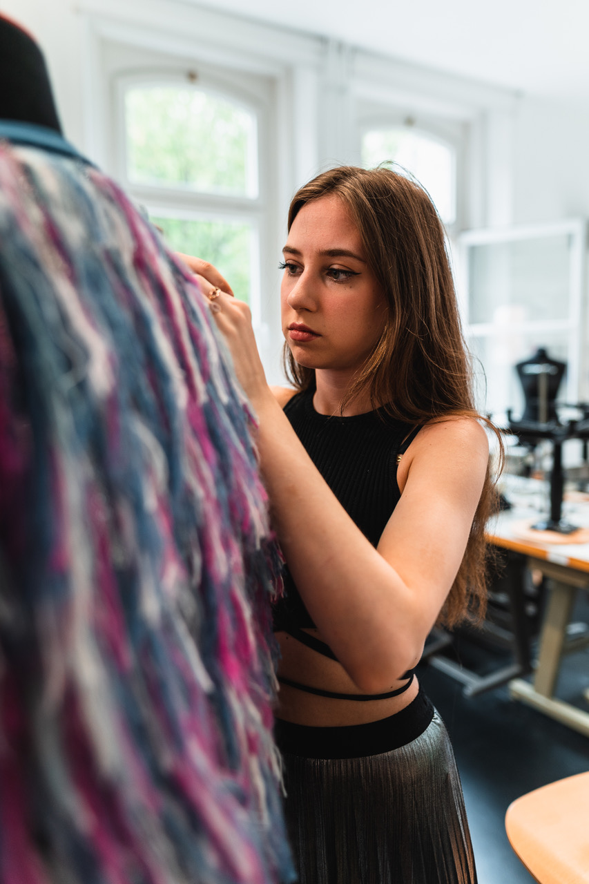 A student at work in the atelier, draping a dress on a mannequin